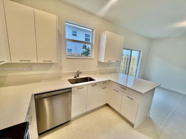 kitchen with a sink, a peninsula, light countertops, and stainless steel dishwasher