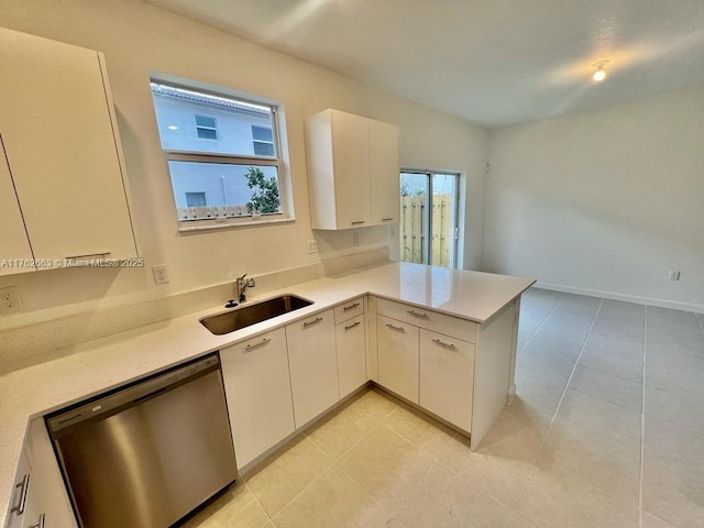 kitchen featuring a wealth of natural light, a sink, a peninsula, light countertops, and dishwasher