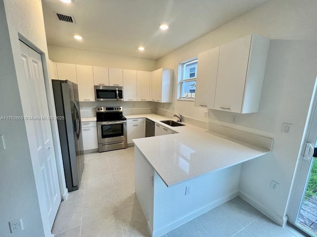 kitchen with visible vents, a peninsula, recessed lighting, a sink, and appliances with stainless steel finishes