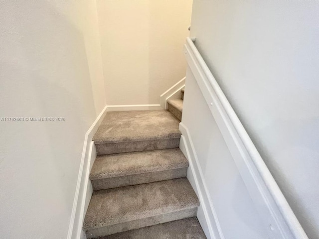 stairway featuring baseboards and carpet flooring