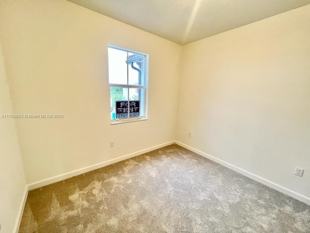 spare room with baseboards and carpet floors