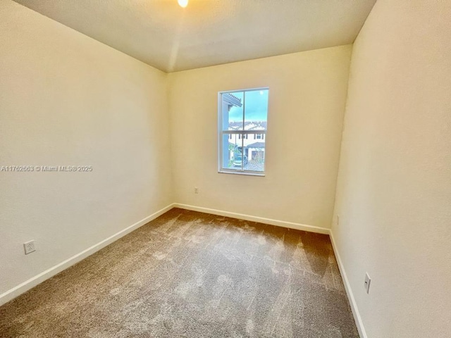 empty room with baseboards and dark carpet