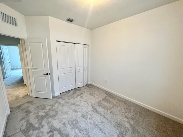 unfurnished bedroom with a closet, visible vents, baseboards, and carpet floors