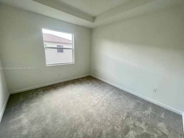 carpeted spare room featuring baseboards