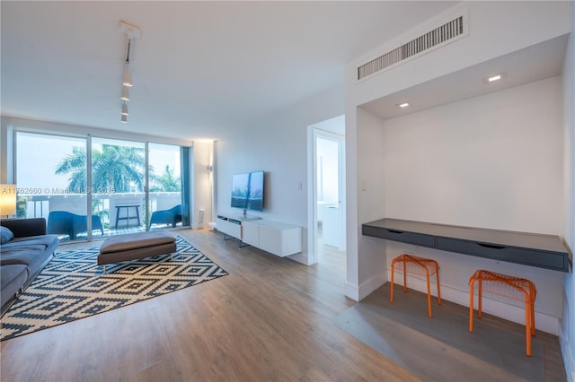 living room with visible vents, track lighting, baseboards, wood finished floors, and a baseboard radiator