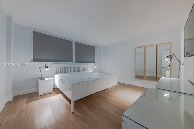 bedroom featuring light wood-style floors and baseboards