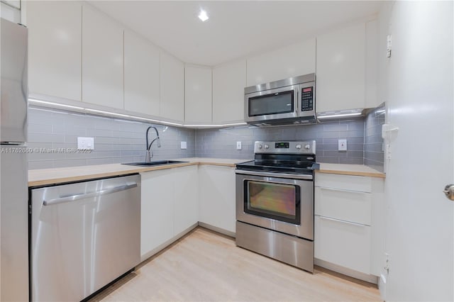 kitchen with decorative backsplash, white cabinets, appliances with stainless steel finishes, and a sink