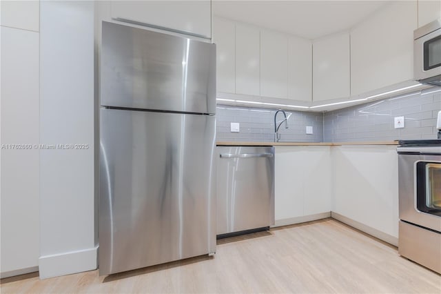 kitchen featuring tasteful backsplash, appliances with stainless steel finishes, white cabinetry, and modern cabinets