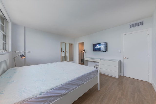 bedroom featuring wood finished floors and visible vents