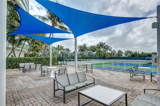 view of patio / terrace featuring a tennis court and fence