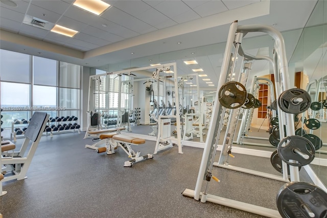 exercise room featuring a paneled ceiling, visible vents, and expansive windows