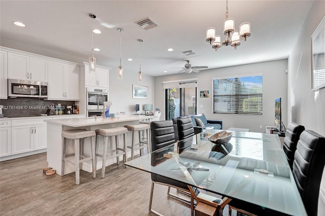 dining space featuring recessed lighting, visible vents, light wood-style floors, and ceiling fan with notable chandelier