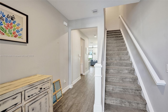 staircase with visible vents, baseboards, and wood finished floors