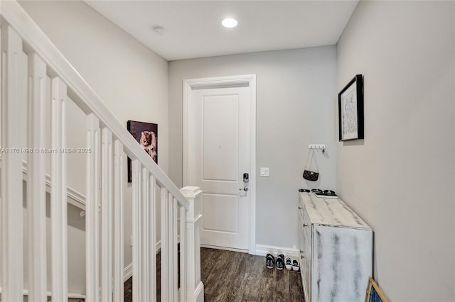 foyer entrance featuring dark wood-type flooring, stairway, and baseboards