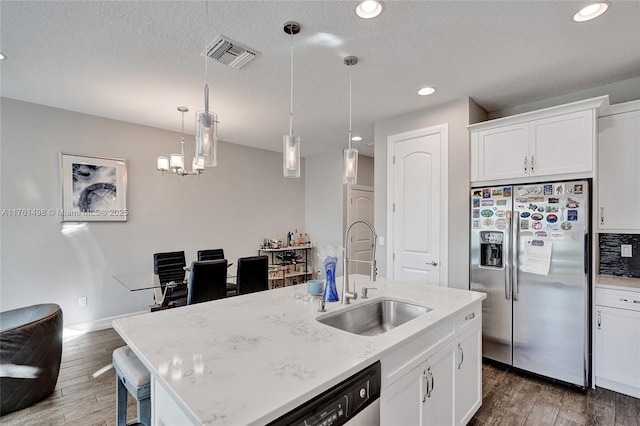 kitchen with wood finished floors, visible vents, a sink, stainless steel refrigerator with ice dispenser, and dishwasher