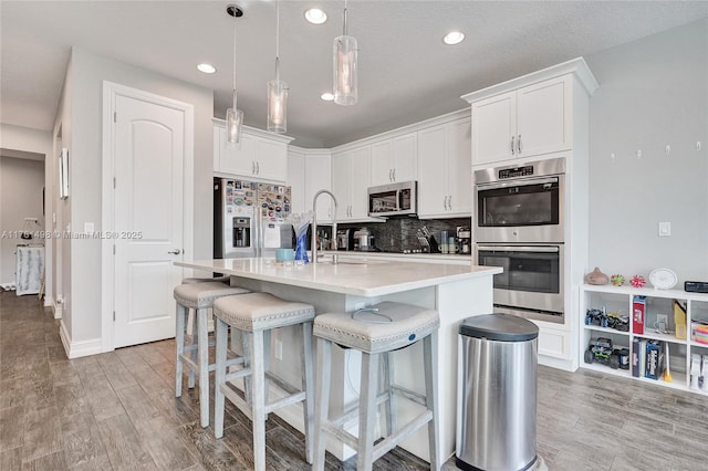 kitchen featuring light countertops, backsplash, light wood finished floors, and stainless steel appliances