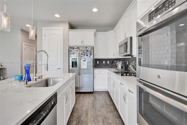 kitchen with a sink, white cabinetry, stainless steel appliances, decorative backsplash, and dark wood-style flooring