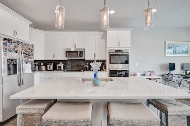 kitchen featuring tasteful backsplash, hanging light fixtures, white cabinets, and stainless steel appliances