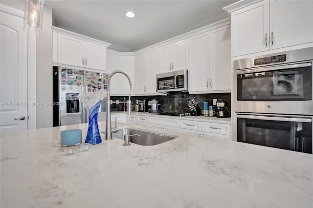 kitchen with decorative backsplash, appliances with stainless steel finishes, white cabinetry, and a sink