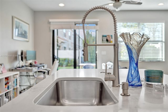 interior details with a ceiling fan, light stone counters, recessed lighting, and a sink