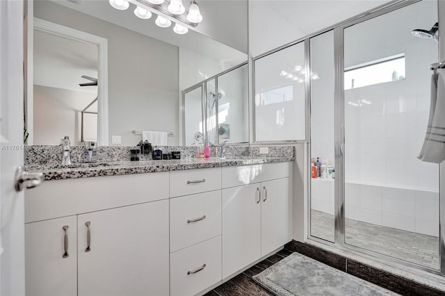 full bathroom featuring double vanity, a stall shower, and a sink