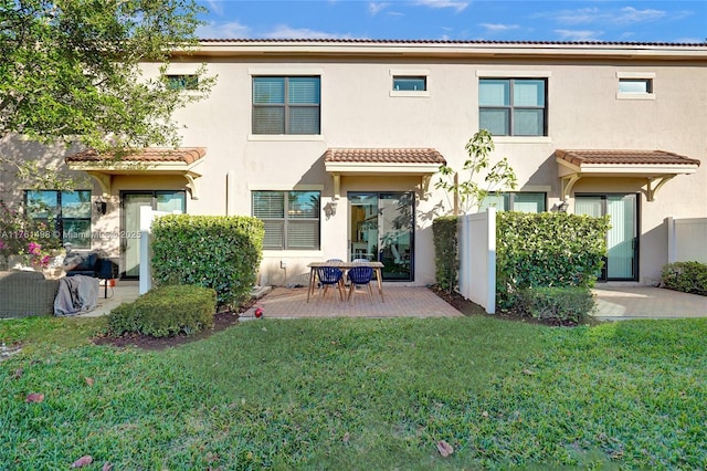 rear view of house with a yard, a patio, a tile roof, and stucco siding