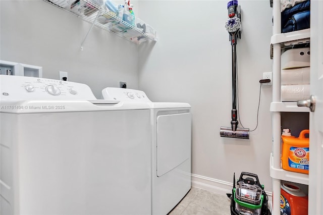 clothes washing area with laundry area, baseboards, tile patterned floors, and washer and clothes dryer