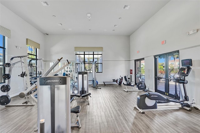 workout area with visible vents, a high ceiling, wood finished floors, and baseboards