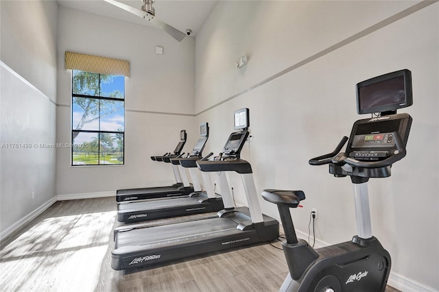 workout area with a high ceiling, baseboards, and wood finished floors