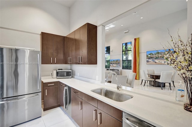 kitchen with recessed lighting, a sink, stainless steel appliances, light countertops, and dark brown cabinetry