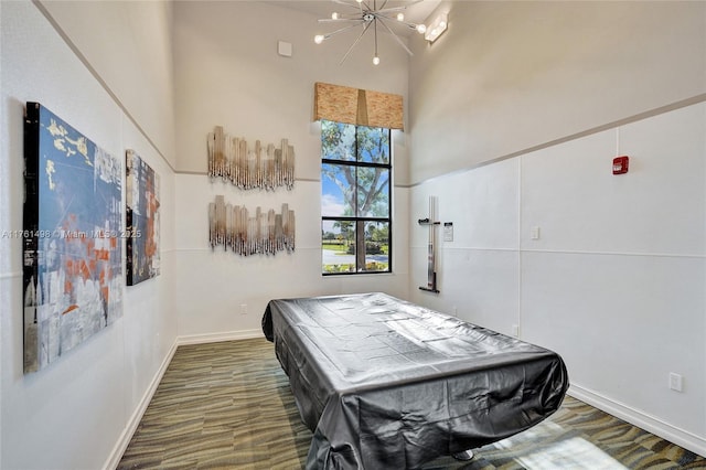 bedroom featuring pool table, baseboards, a towering ceiling, wood finished floors, and a notable chandelier