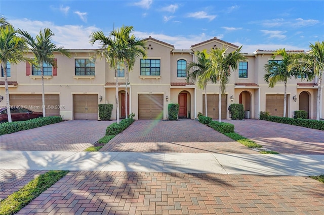 townhome / multi-family property with stucco siding, driveway, and an attached garage