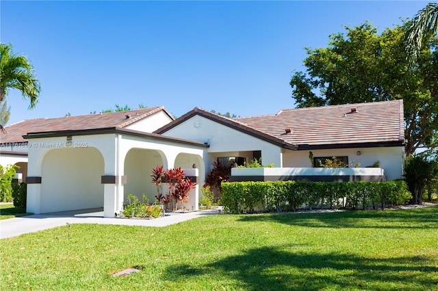 mediterranean / spanish-style house with a front yard, a carport, and stucco siding