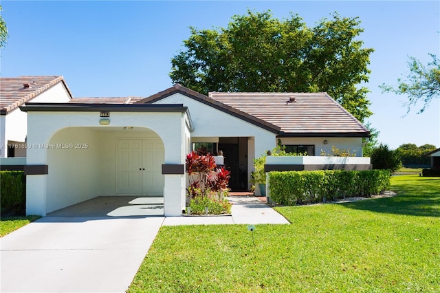 view of front of home featuring a front yard, a tile roof, stucco siding, and concrete driveway