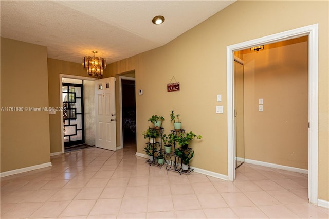 entryway with baseboards, light tile patterned floors, a textured ceiling, and an inviting chandelier