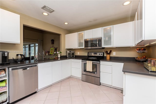 kitchen featuring dark countertops, white cabinets, visible vents, and stainless steel appliances