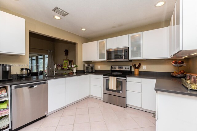 5602 E Parkwalk Cir E Unit 0, Boynton Beach, FL 33472 - kitchen featuring appliances with stainless steel finishes, dark countertops, white cabinetry, glass insert cabinets, and recessed lighting