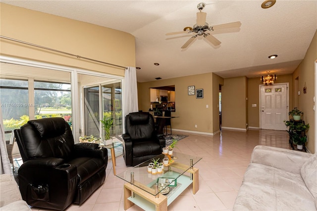 living area featuring baseboards, a textured ceiling, light tile patterned flooring, and ceiling fan with notable chandelier