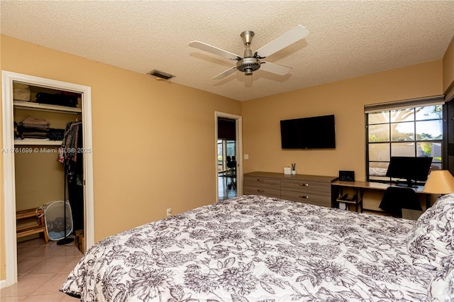 bedroom with a walk in closet, a textured ceiling, light tile patterned floors, and visible vents