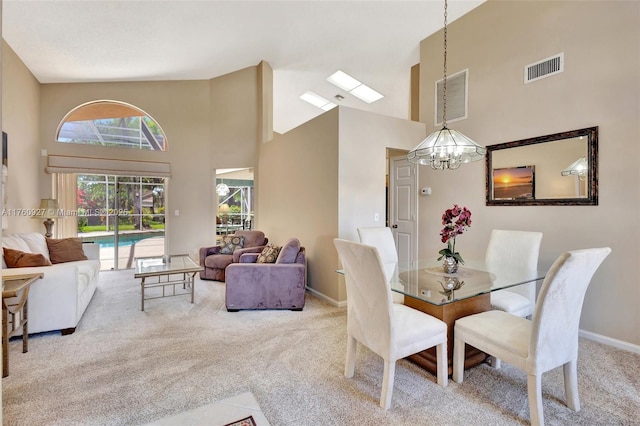 carpeted dining room featuring high vaulted ceiling, visible vents, and a chandelier