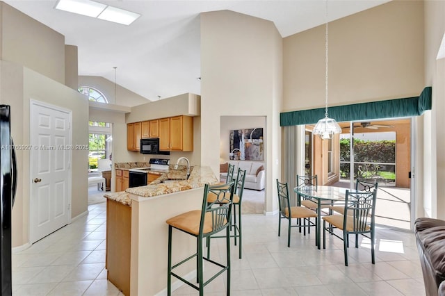 kitchen with a sink, electric range oven, light tile patterned flooring, black microwave, and light stone countertops