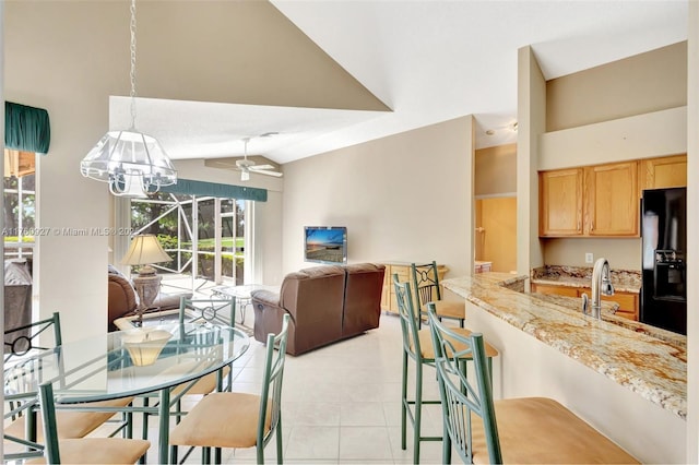 dining area with vaulted ceiling, light tile patterned floors, and ceiling fan with notable chandelier