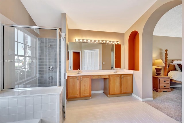 full bathroom featuring double vanity, baseboards, a tile shower, and a sink