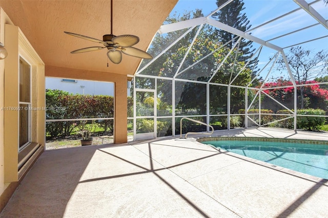 outdoor pool with glass enclosure, a patio, and ceiling fan