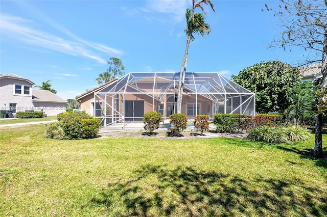 back of property with glass enclosure, a yard, and stucco siding