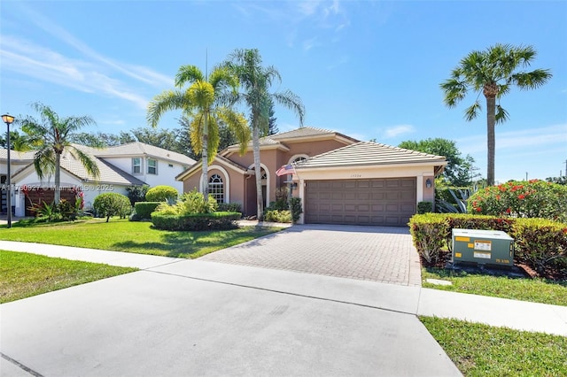 view of front of house with decorative driveway, a garage, a front lawn, and stucco siding