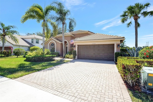view of front of house with a front lawn, a tile roof, stucco siding, decorative driveway, and a garage