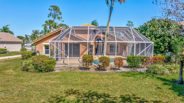 rear view of house with stucco siding, a lawn, a patio, glass enclosure, and an outdoor pool