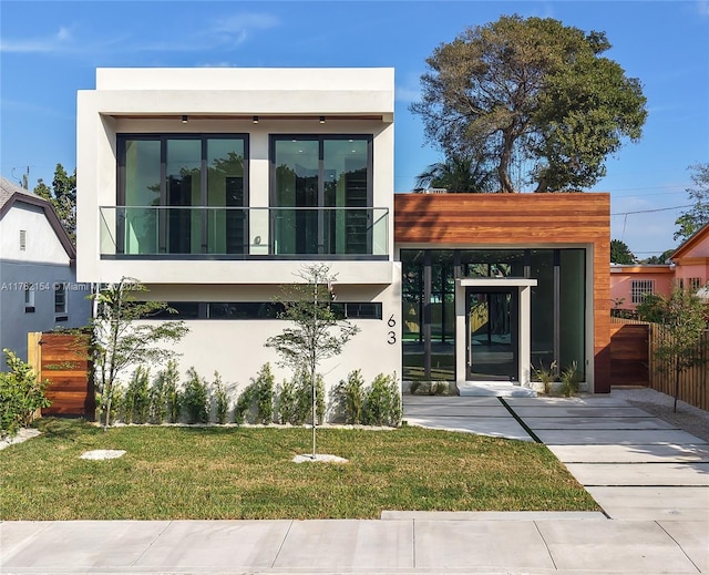 contemporary home with stucco siding and a front yard