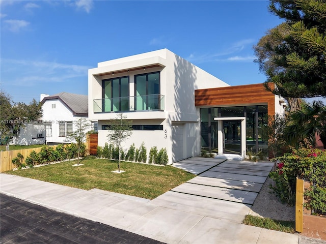 contemporary home with stucco siding, a front lawn, and fence